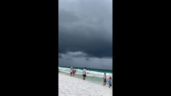Storm clouds build as people swim near Miramar Beach, Walton, Florida