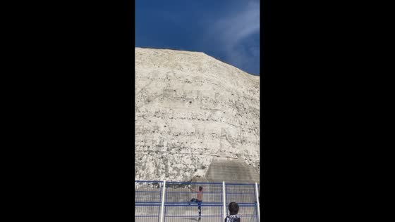 Man kicks ball over cliff after kid’s challenge in Brighton, England, UK