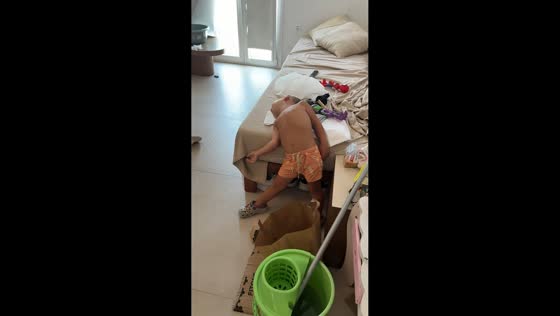 Sleepy toddler dozes off while leaning against bed in Mykonos, Greece