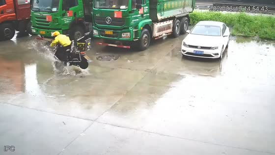 Motorcycle rider falls into flooded pothole on slippery road in Zhejiang, China