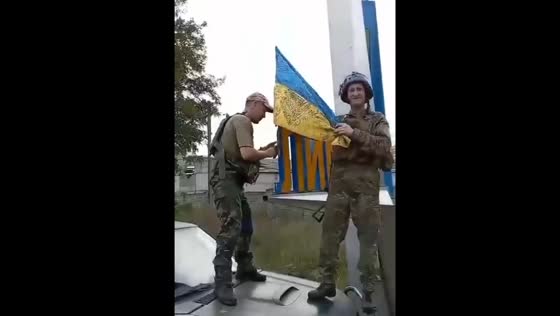 Ukrainian military raising the Ukrainian flag at the entrance to Liman
