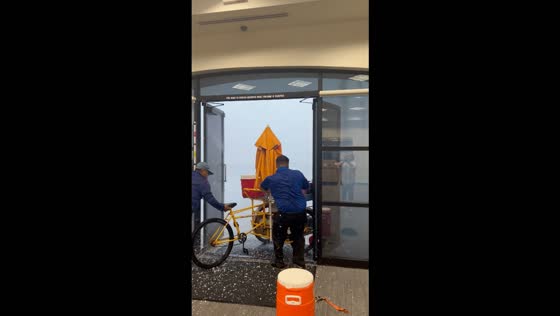 Manager helps street food vendor bring his cart inside during a severe storm in Peoria, USA