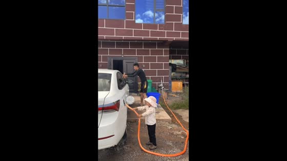 Child pours water into car fuel tank while father cleans the vehicle in Qinghai, China