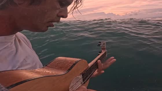 Person plays music while surfing in Lombok, Indonesia