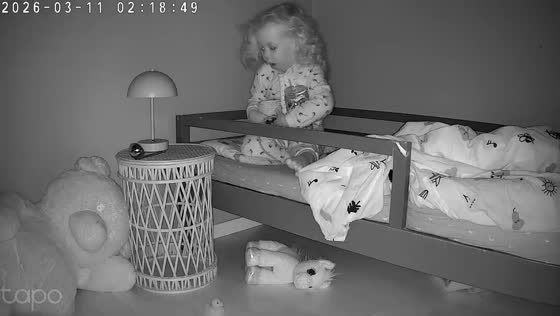 Toddler carefully organizes toys on bed in adorable moment in Norway